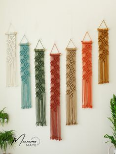 four macrame wall hangings in various colors and sizes on a white wall