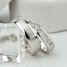 two white gold wedding rings with diamonds on top and in between the ring is an ice cube