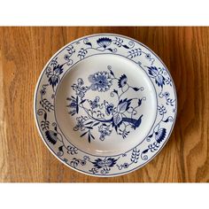 a blue and white plate sitting on top of a wooden table next to a wall