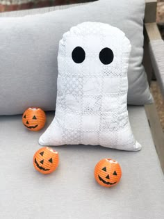 two pumpkins sitting on top of a couch next to a white pillow with black eyes