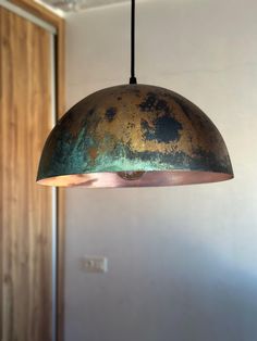 an old light hanging from a ceiling in a room with white walls and wood paneling