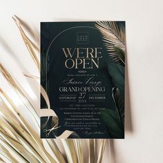 a black and gold wedding card with palm leaves on the front, in an elegant style