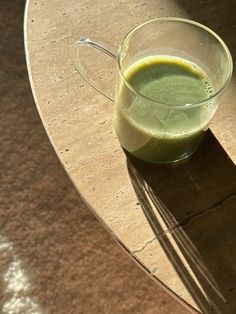 a glass cup filled with green liquid sitting on top of a table