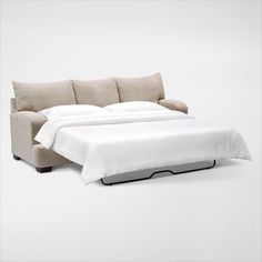 a bed that is sitting on top of a white floor next to a couch with pillows