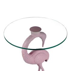 a glass table with a pink flamingo figurine sitting on it's legs