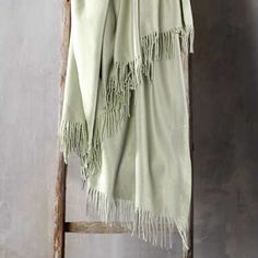 a green blanket hanging on a wooden ladder