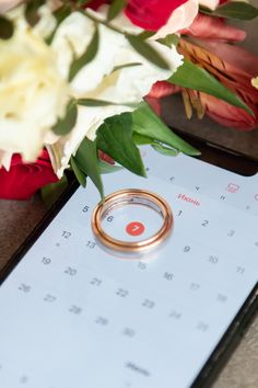 a wedding ring sitting on top of a calendar next to flowers