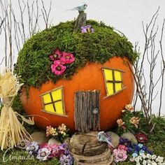 a pumpkin shaped house made out of moss and flowers with a bird perched on the roof