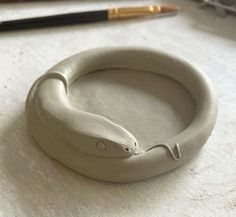 a close up of a ring on a table with a pen and pencil in the background