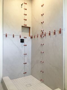 a bathroom with marble walls and tile flooring in the shower area, along with red clips attached to the wall