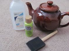 a brown teapot sitting on top of a carpet next to a bottle of cleaner