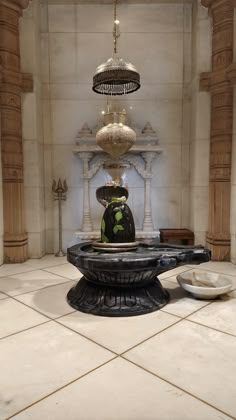 a fountain in the middle of a room with chandelier above it