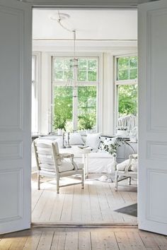 an open door leading to a living room with white furniture