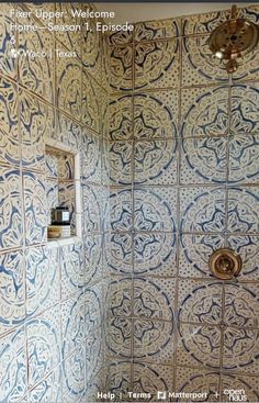 a bathroom with blue and white tile on the walls, shower head and hand held faucet