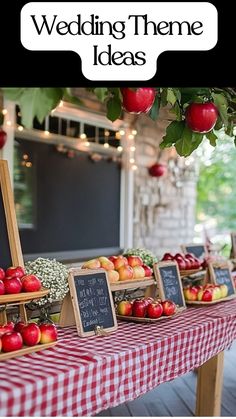 Rustic apple-themed wedding table with a red and white checkered tablecloth. Fresh apples, wooden crates, chalkboard signs, and small white floral arrangements create a charming country-inspired wedding decor.