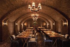 a dining room with tables and chairs in an old brick tunneled building, lit by candles