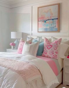 a white bed with pink and blue pillows