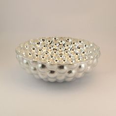 a silver bowl sitting on top of a white table