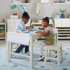 two children sitting at a table playing with toys