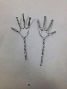 two metal hair clips sitting on top of a white table