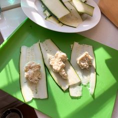 sliced cucumbers and cheese on a green cutting board next to a white plate