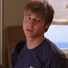 a young man wearing a blue shirt looking at the camera