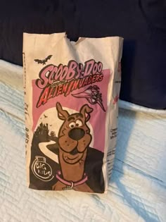 a bag that is sitting on top of a bed with the words scoo - doo adventures written on it