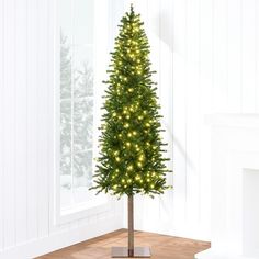 a small christmas tree is lit up in the living room with white walls and wood flooring