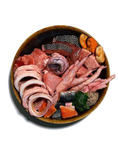 a bowl filled with meats and vegetables on top of a white table next to a knife