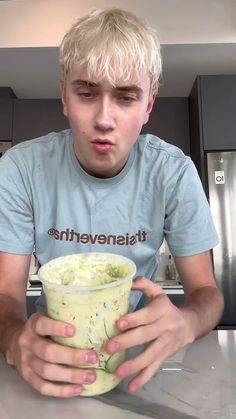 a man sitting at a table with a cup in front of him and making a face