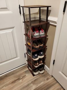 there is a shoe rack with many pairs of shoes on it in front of the door