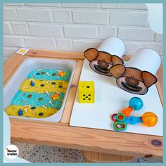 a wooden table topped with a tray filled with blue and yellow cake next to sunglasses on top of it