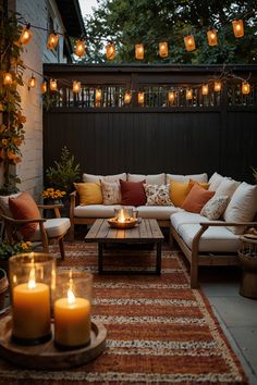 an outdoor living room with candles lit on the table and couches in front of it