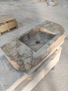 a marble sink sitting on top of a wooden table in the middle of a room