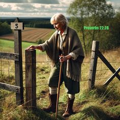 an old woman leaning on a fence with a stick in her hand and looking at the ground