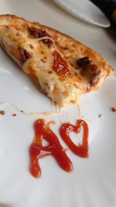 a slice of pizza on a plate with ketchup drizzled around it