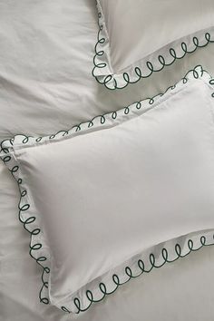 two white pillows with green trim on them