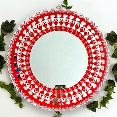 a red and white plate sitting on top of a table next to green plant life