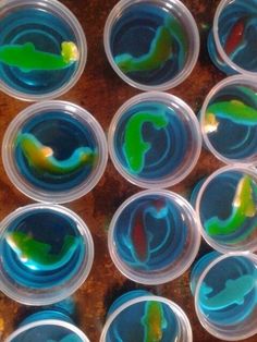 several plastic cups filled with different colored liquids on top of a wooden table next to each other