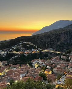 an aerial view of a small town with mountains in the background at sunset or dawn