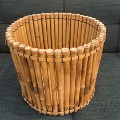 a close up of a basket made out of bamboo sticks on a gray couch cushion