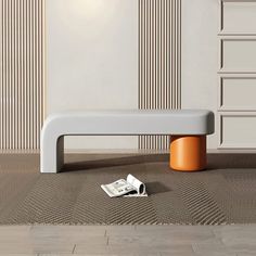 a white bench sitting on top of a wooden floor next to a wall with striped walls