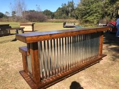 an old metal and wood bar in the middle of a field with other wooden benches