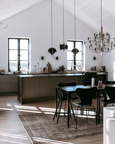 an open kitchen and dining room area in a house with white walls, wood floors, and black chairs