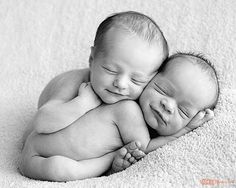 two newborn babies cuddle together on a white blanket in black and white photo studio