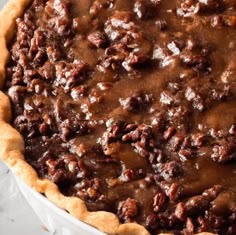 a pecan pie with chocolate toppings in a white dish on top of a table