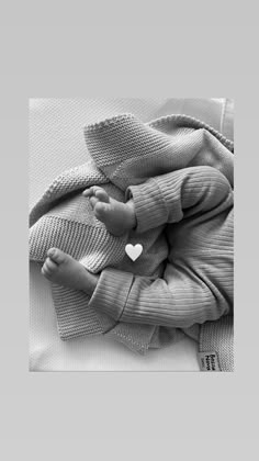 a black and white photo of a baby wrapped in a blanket with a heart on it