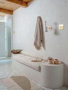 a white bench sitting next to a wall mounted coat rack and towel on top of it