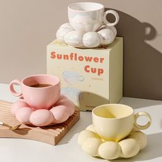 a pink coffee cup sitting next to a box of sunflower cups on a table