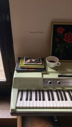 there is a coffee cup sitting on top of the piano and it's music